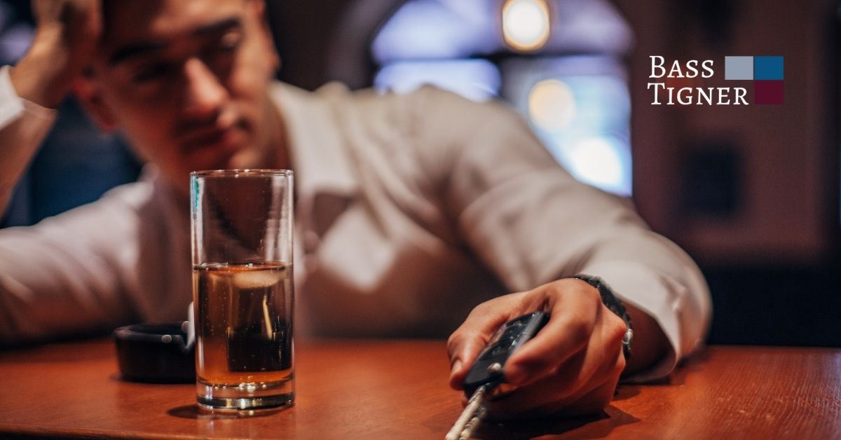 Man at bar drinking and holding a key.