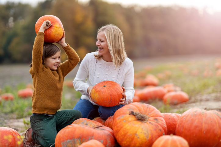 mother and child playing at pumpkin patch